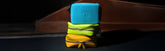 Three colorful pouches stacked on top of each other, with the top pouch being blue, the middle pouch green, and the bottom pouch yellow.