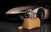 Zwei schwarz-gelbe Armbänder mit transparenten Verschlüssen liegen auf einer dunklen, reflektierenden Oberfläche vor einem gelb-schwarzen geometrischen Hintergrund. | Lamborghini Store | Official Website